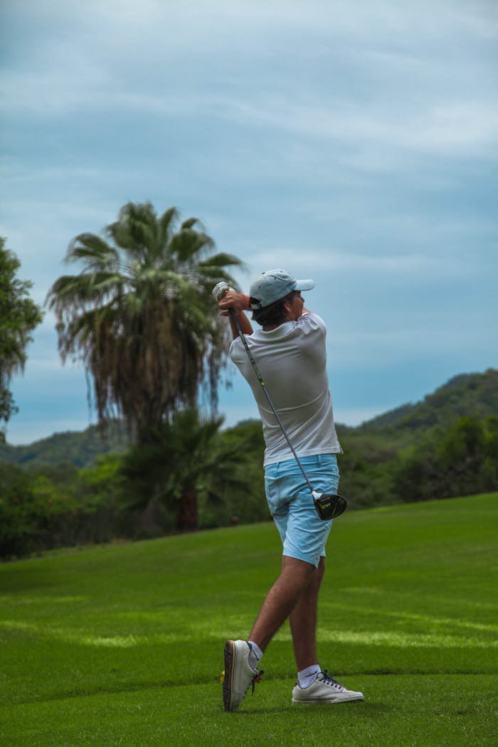 Man playing golf in lush Puerto Vallarta landscape showcasing vibrant greenery and palm trees.